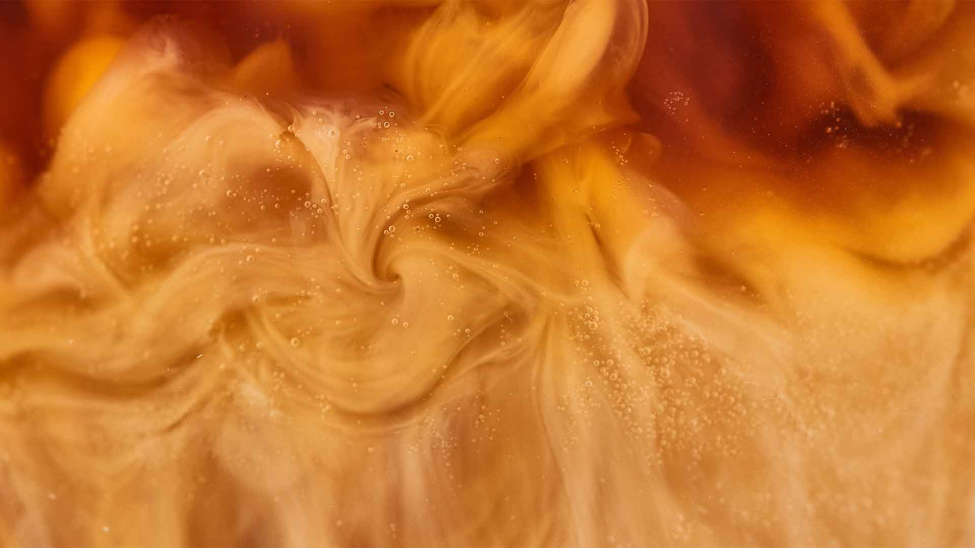 close up view of brown coffee mixing with milk in glass, panoramic shot